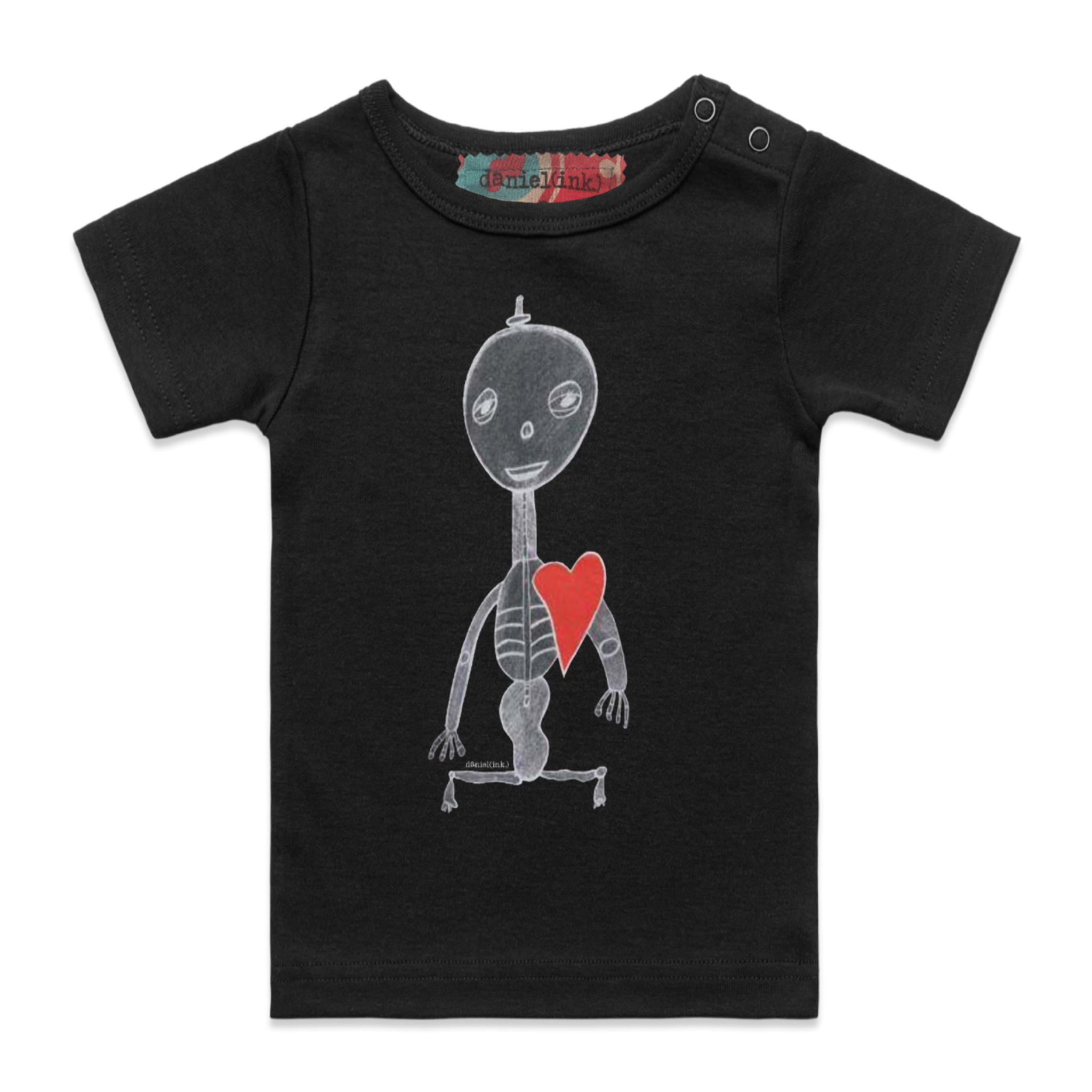 Black short sleeve babies’ t-shirt featuring a hand drawn sketch of a skeleton with a red heart. The t-shirt has a red, white, and blue fabric label on the back of the neck and has two black press studs on the left shoulder.